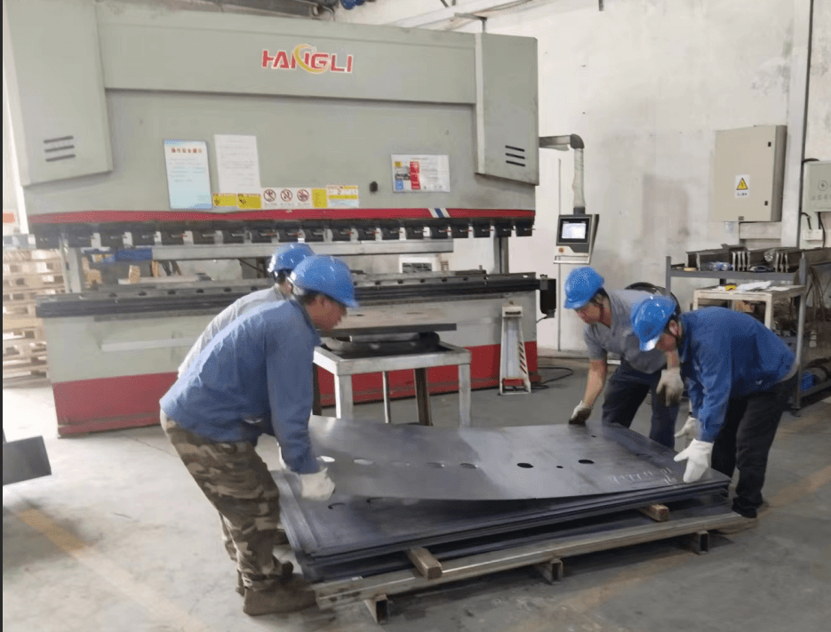 Workers handling large sheet metal at CNC bending station
